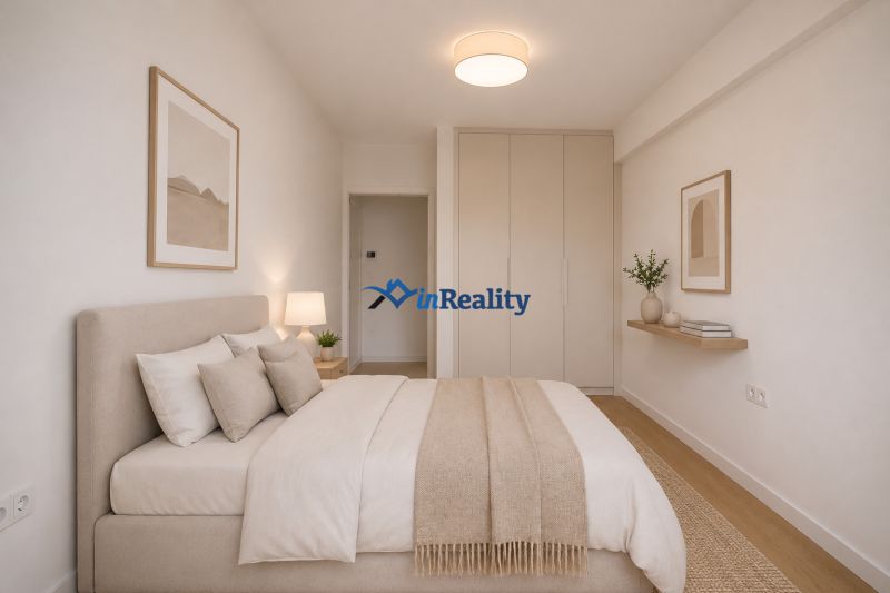 A bright bedroom in a two-room apartment with a bed and storage space.