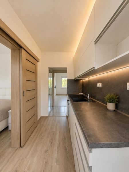 A kitchen in a 2-room apartment with a wooden decor floor and sliding doors.