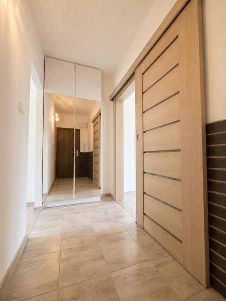 A hallway with tiles, sliding doors, and a mirrored wardrobe in a 2-room apartment.