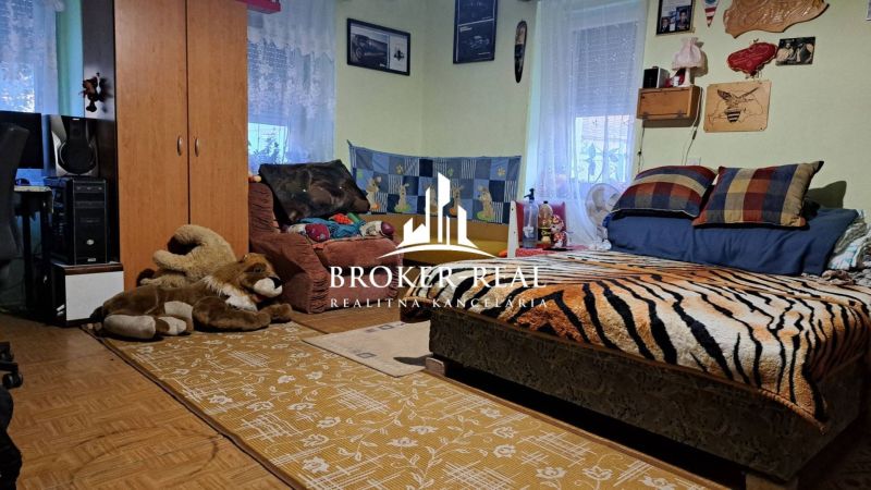 A room in a family house with a decorative throw and plush toys on the floor.
