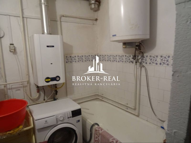Bathroom in a family house with a gas boiler, washing machine, and bathtub.