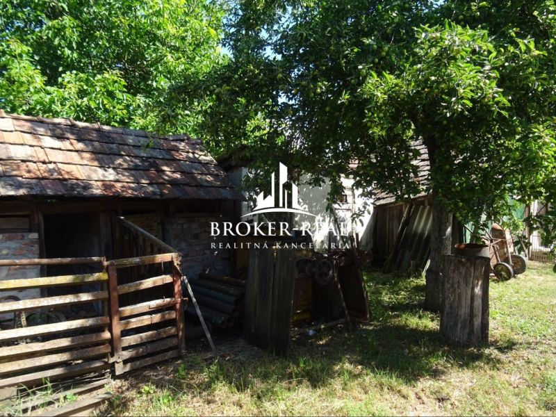 The courtyard of a family house in Abaujvár with a wooden shelter and trees.