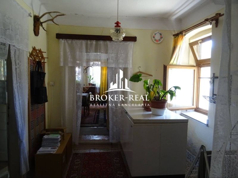 An old hallway of a family house with plants and curtains on the windows.