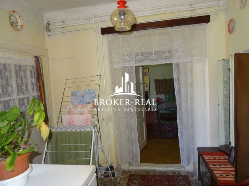 Interior of a family house with a lace curtain, a plant, and a clothes drying rack.