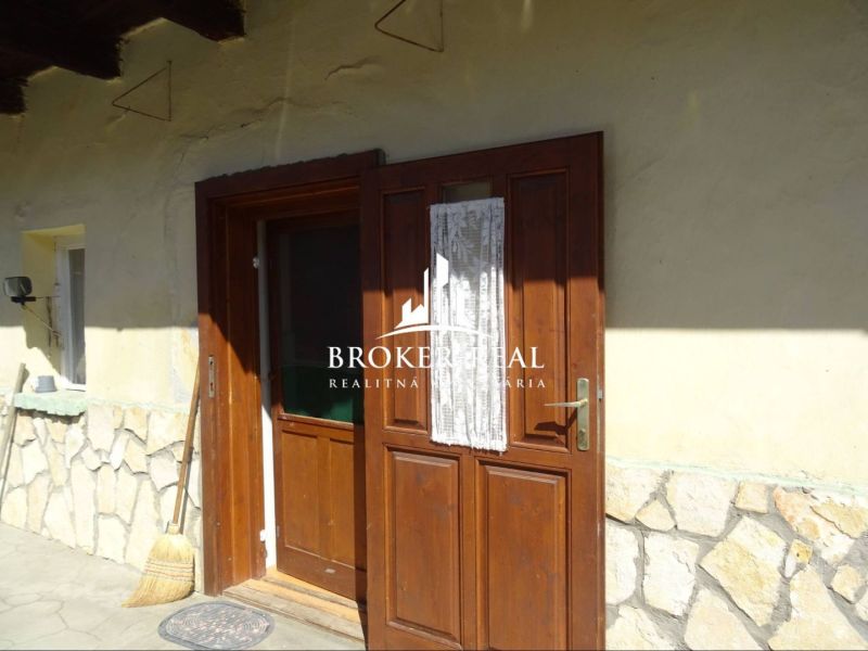 Wooden door with decorative glass, broom, and stone cladding in a family house in Abaujvár.