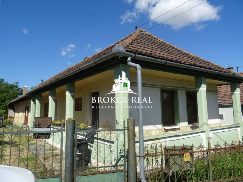 A family house in Abaujvár with a traditional roof and a green facade under a blue sky.