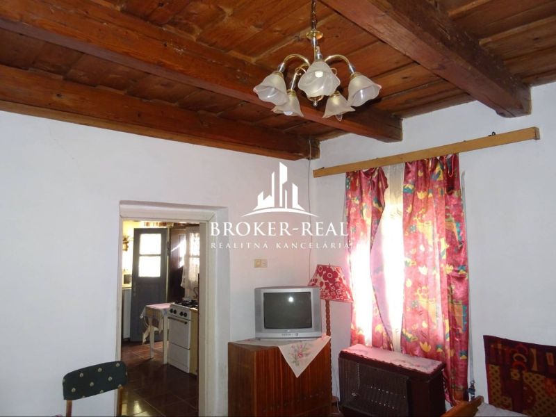 Interior of a family house with a wooden ceiling, television, and colorful curtains.