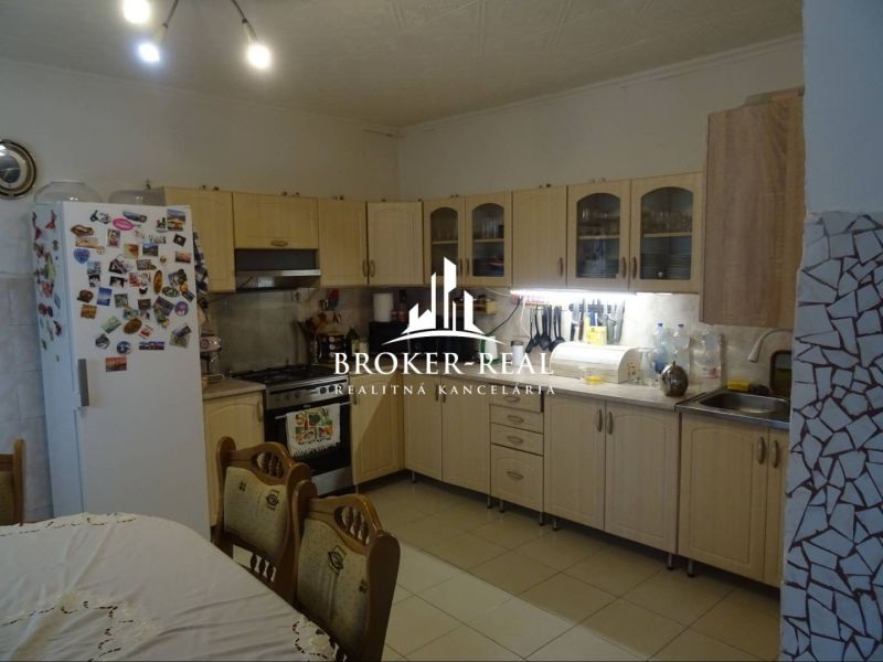 Kitchen interior with wooden decor in a family house, dominated by a light-colored kitchen unit.