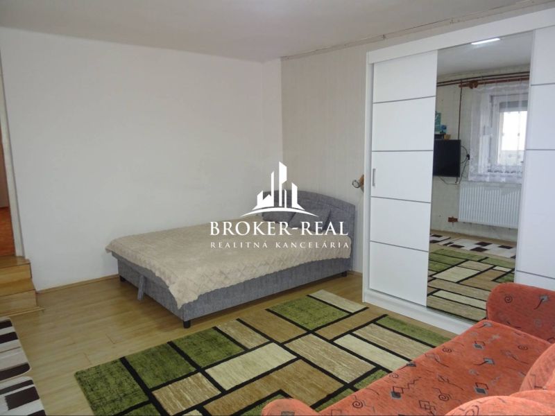A room in a family house with a bed and sliding doors, a floor with a wood decor.