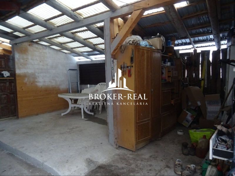 The exterior of a family house in Gönc with a plastic table and chairs under a roof structure.