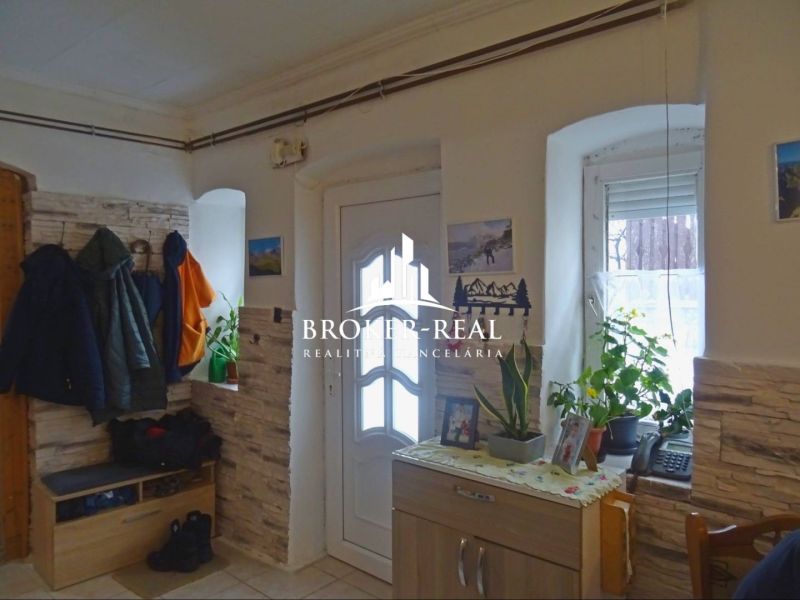Interior of a family house with entrance doors, stone cladding, and coat hooks.