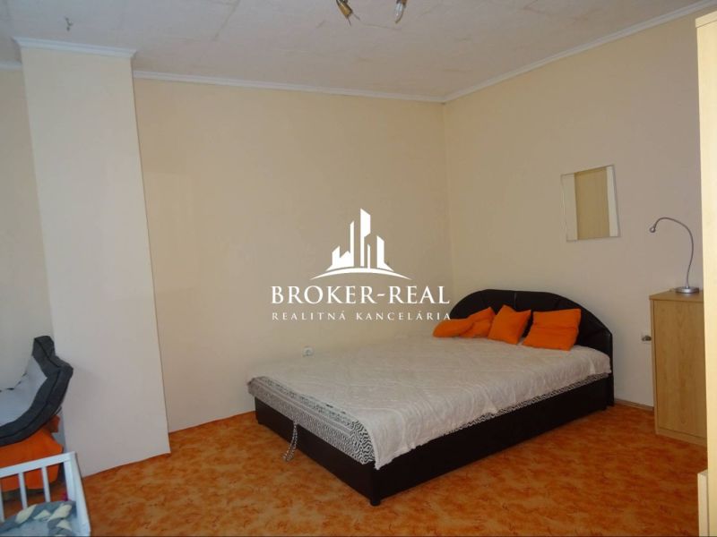 A bedroom in a family house with an orange carpet and a double bed.