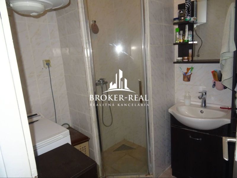 Bathroom with a sink, shower, and washing machine in a family house.