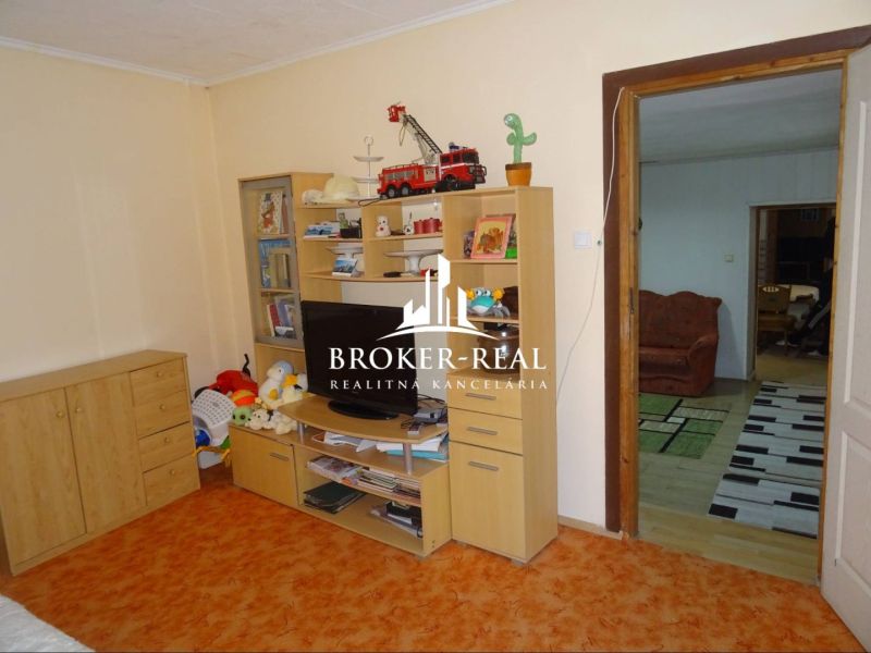 A room with a storage wall, a television, and open doors in a family house.