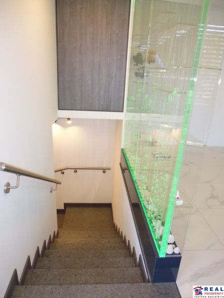 Stairs with handrails next to a glass wall, floor with wood decor in warehouses and halls.