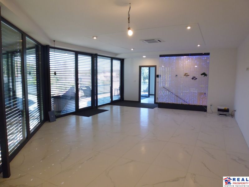 Interior with large windows, white tiles, and a floor with a wooden design.
