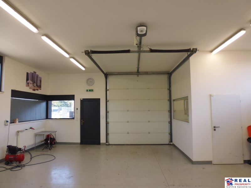 Interior of warehouses and halls with white walls, a garage door, and lighting.