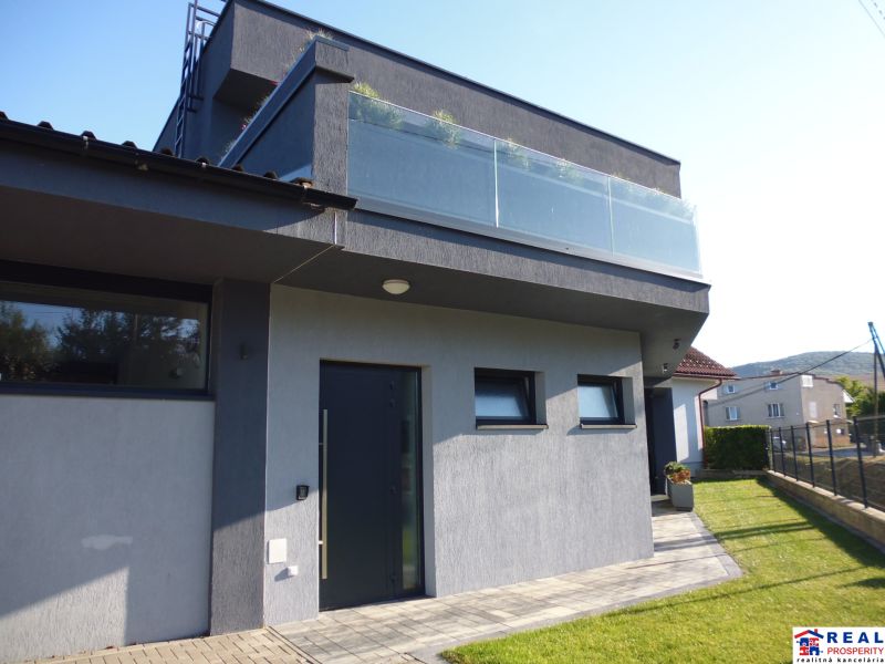 A modern house with a terrace and glass in Kračúnovce, surrounded by green grass.