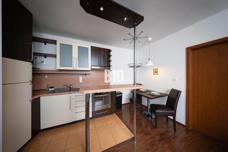 Kitchen unit and dining area in a 2-room apartment with a wooden decor floor.