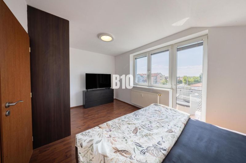 A bright bedroom with a TV in a two-room apartment, wooden decor flooring.