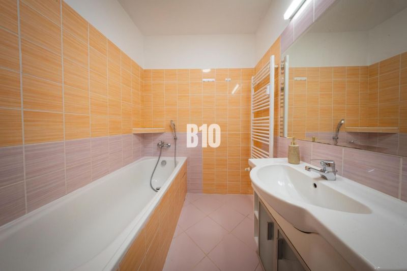 A bathroom in a 2-room apartment with a bathtub and orange tiles.