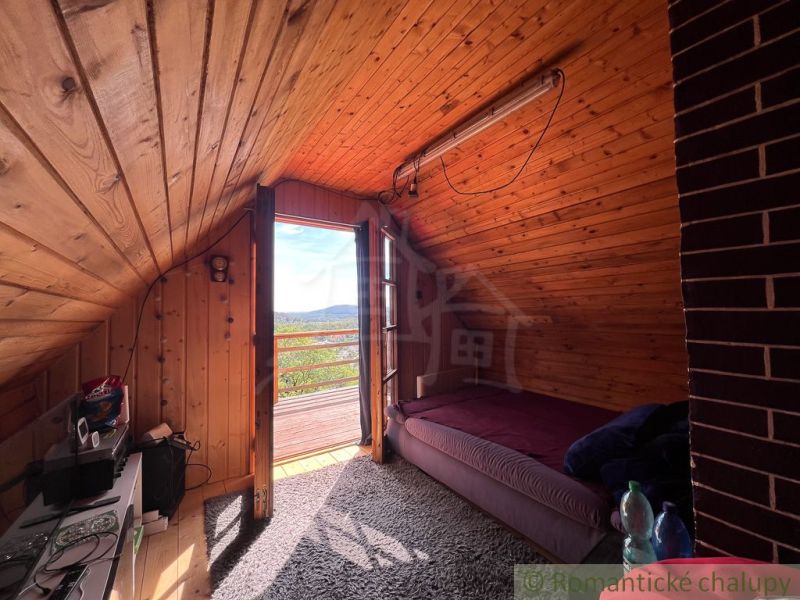 The attic of the cottage with a sloped ceiling and a view of the surrounding landscape.