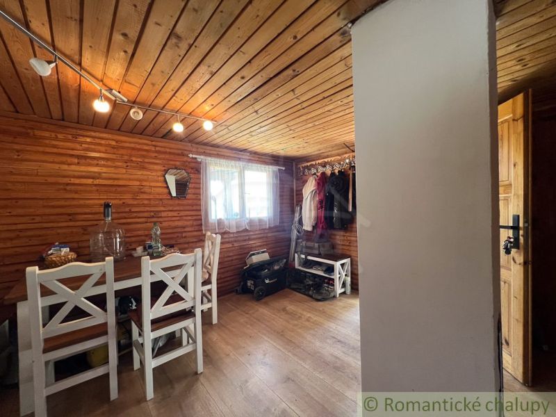 The interior of a cabin with wooden paneling, a table and chairs, and a floor with a wooden decor.