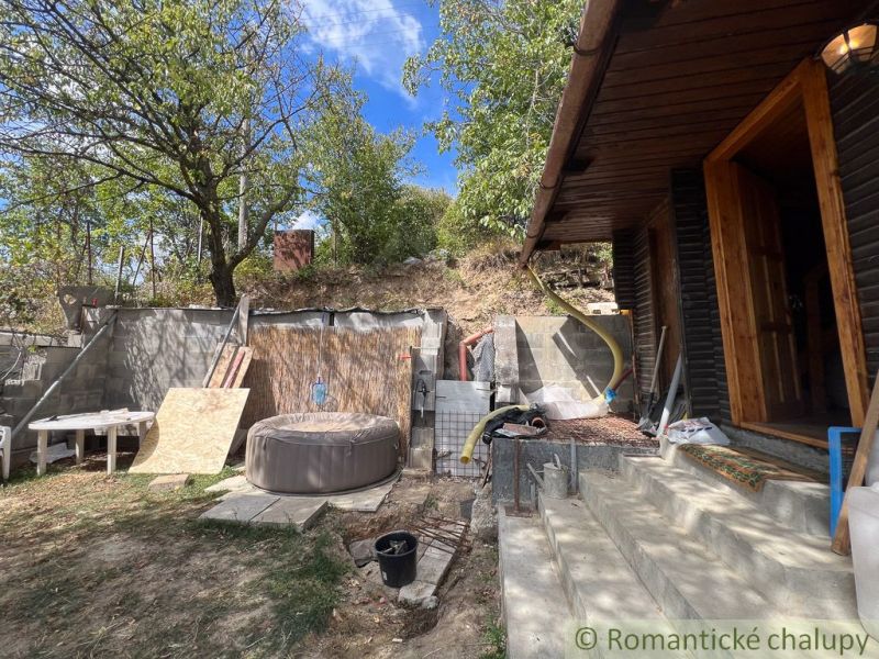 The exterior of the cottage in Bratislava IV with a hot tub, stairs, and greenery.