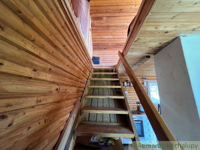 Wooden stairs leading to the attic in a cabin with wooden decor.