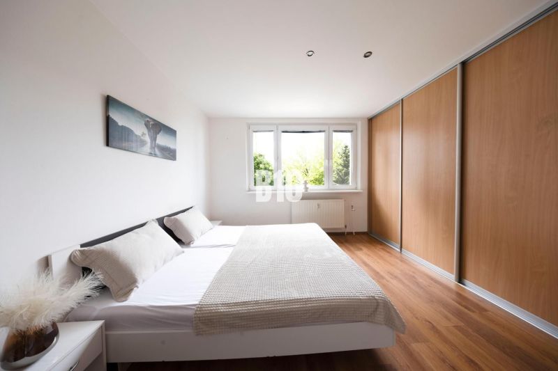 A bright bedroom in a 3-room apartment with a large wardrobe and a wooden decor floor.