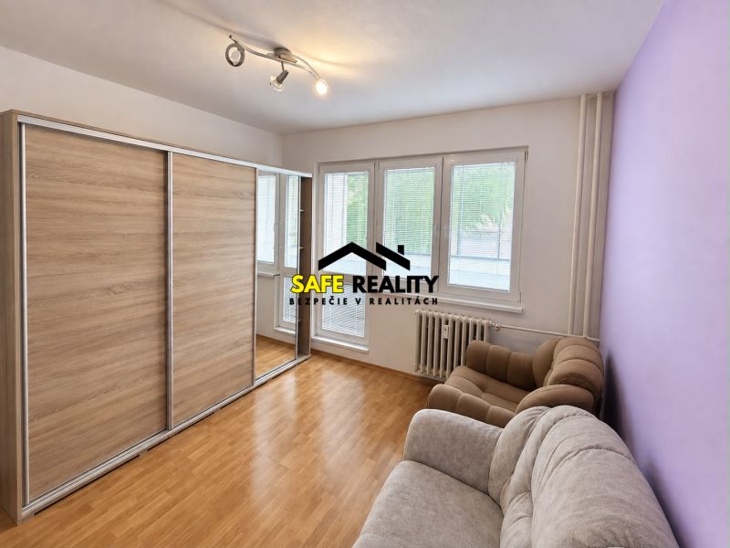 Living room in a 3-room apartment with a sofa and a wardrobe, wooden decor flooring.