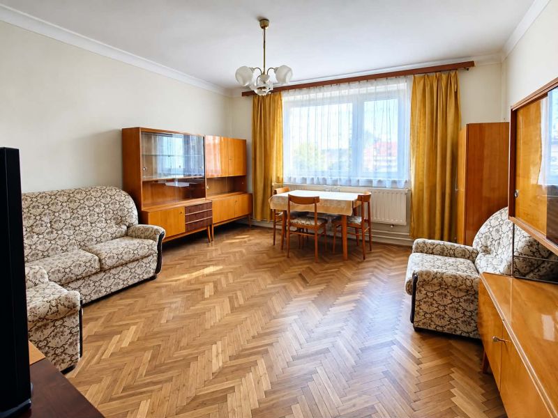 A living room in a family house with antique furniture and a wood-patterned floor.