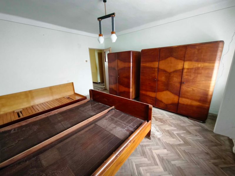 A bedroom in a family house with a wooden decor floor, beds, and wardrobes.