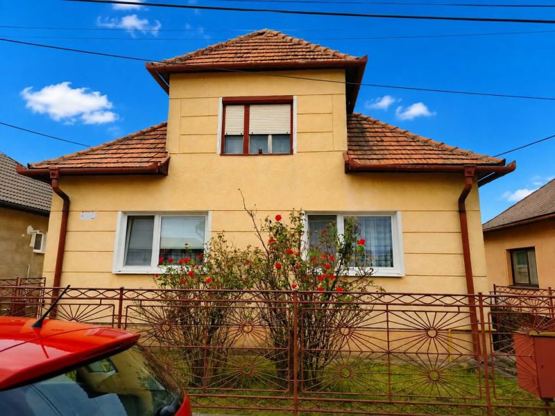 A family house in Oslany with a brick roof and a decorative fence.
