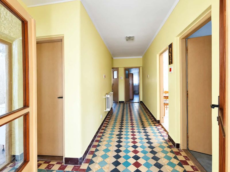A hallway in a family house with colorful tiles and wooden doors.