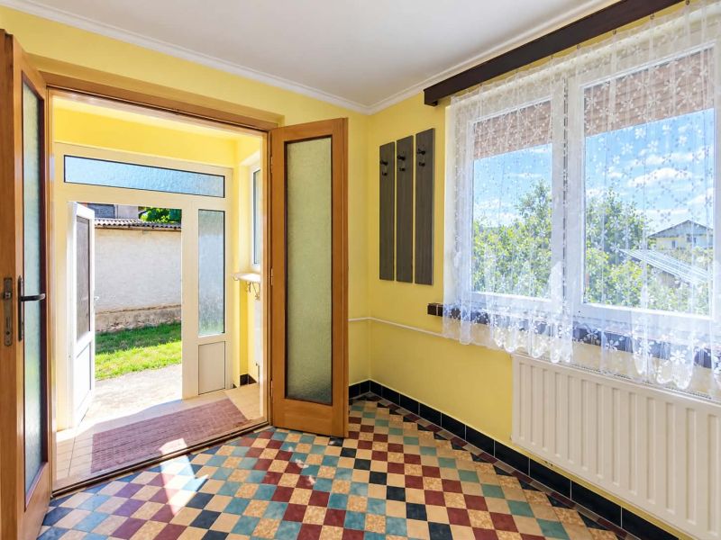 The entrance hall of a family house with colorful tiles and large windows.