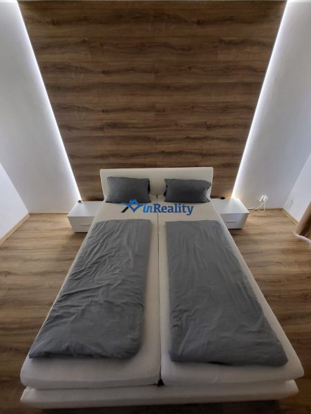 A bedroom with a light-colored bed, gray bedding, and a wooden-patterned floor in a 4-room apartment.