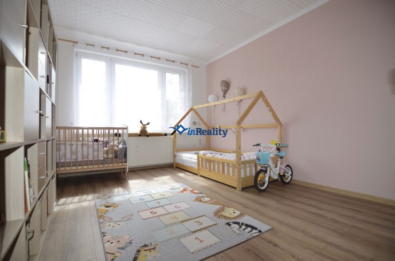 Children's room with wooden decor flooring in a 4-room apartment, playful rug.