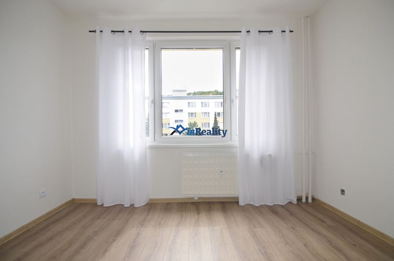 A bright room with a wood-decor floor in a 4-room apartment with curtains.