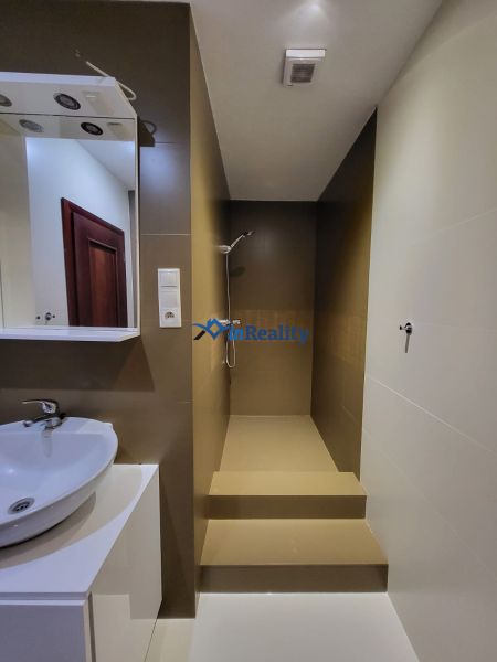 A bathroom with dark tiles, a sink, and a shower in a 4-room apartment.