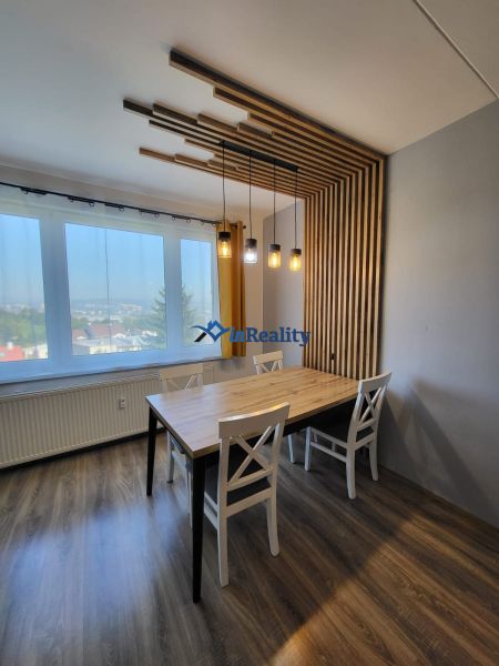 Dining area in a 4-room apartment with wood-patterned flooring and designer lighting.