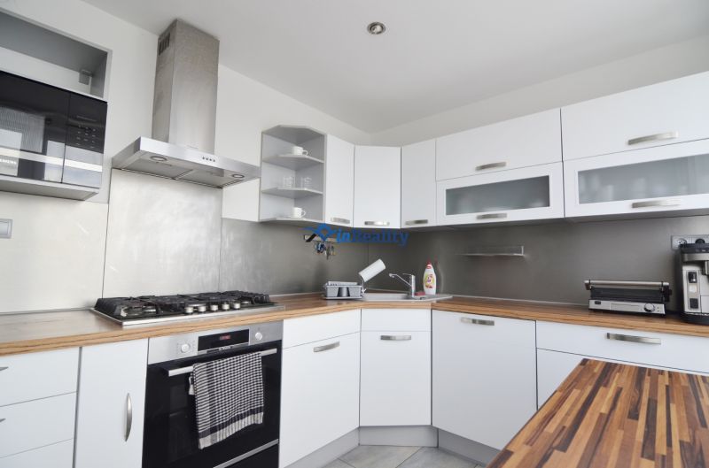 A kitchen in a 4-room apartment with white cabinets and stainless steel appliances.