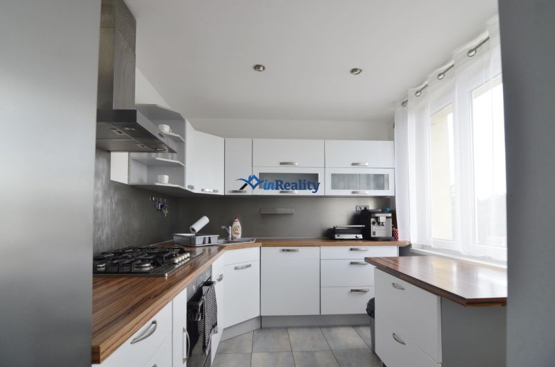 A kitchen in a 4-room apartment with built-in appliances and a floor with a wooden decor.
