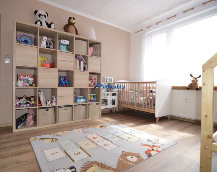 Children's room in a 4-room apartment with a wooden decor floor, shelving storage space, and toys.