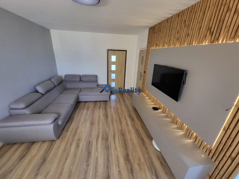 Living room with a large sofa and television in a 4-room apartment, floor with wood decor.