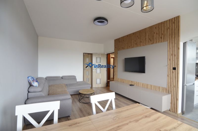 Living room with a gray sofa and wood-patterned flooring in a four-room apartment.
