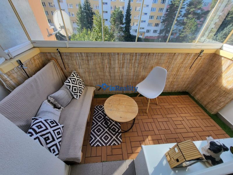 Balcony with seating and flooring with a wood decor in a 4-room apartment.