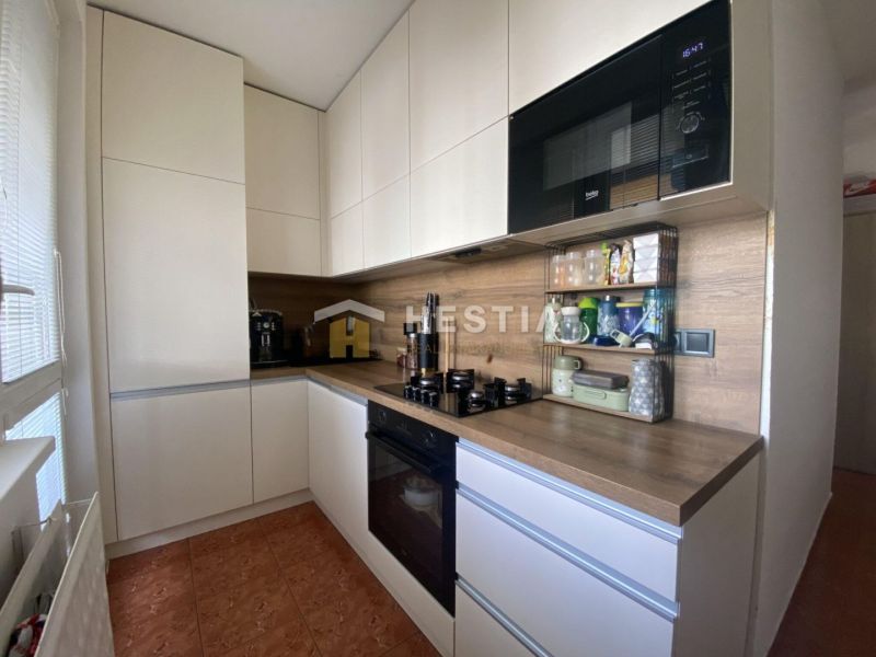 A kitchen in a 2-room apartment with white cabinets and a wooden decor.