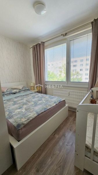 Bedroom in a two-room apartment with large windows and a wooden decor floor.