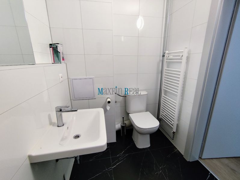 White bathroom with toilet and black floor in the office.